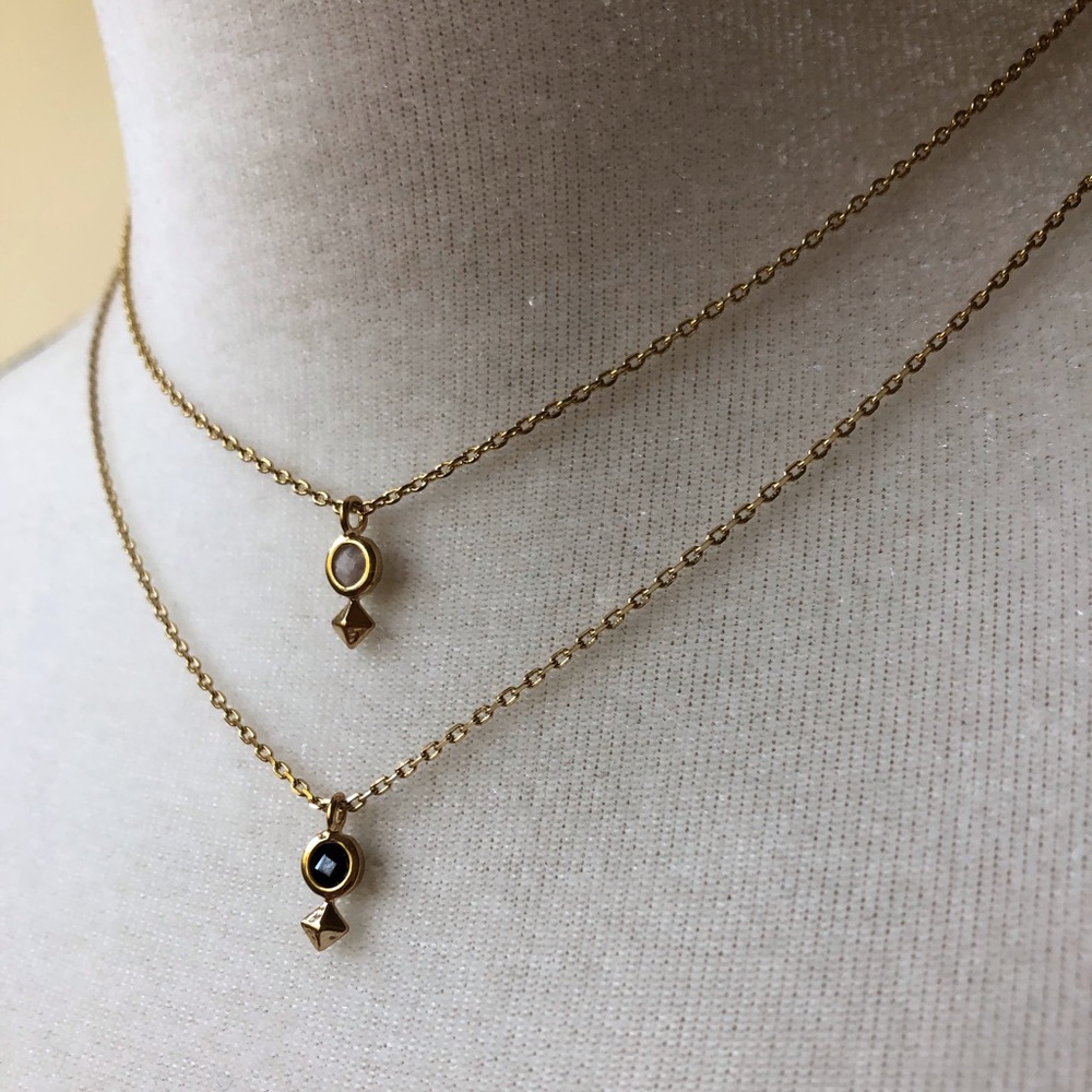 Gold pendant necklace with a black crystal center.